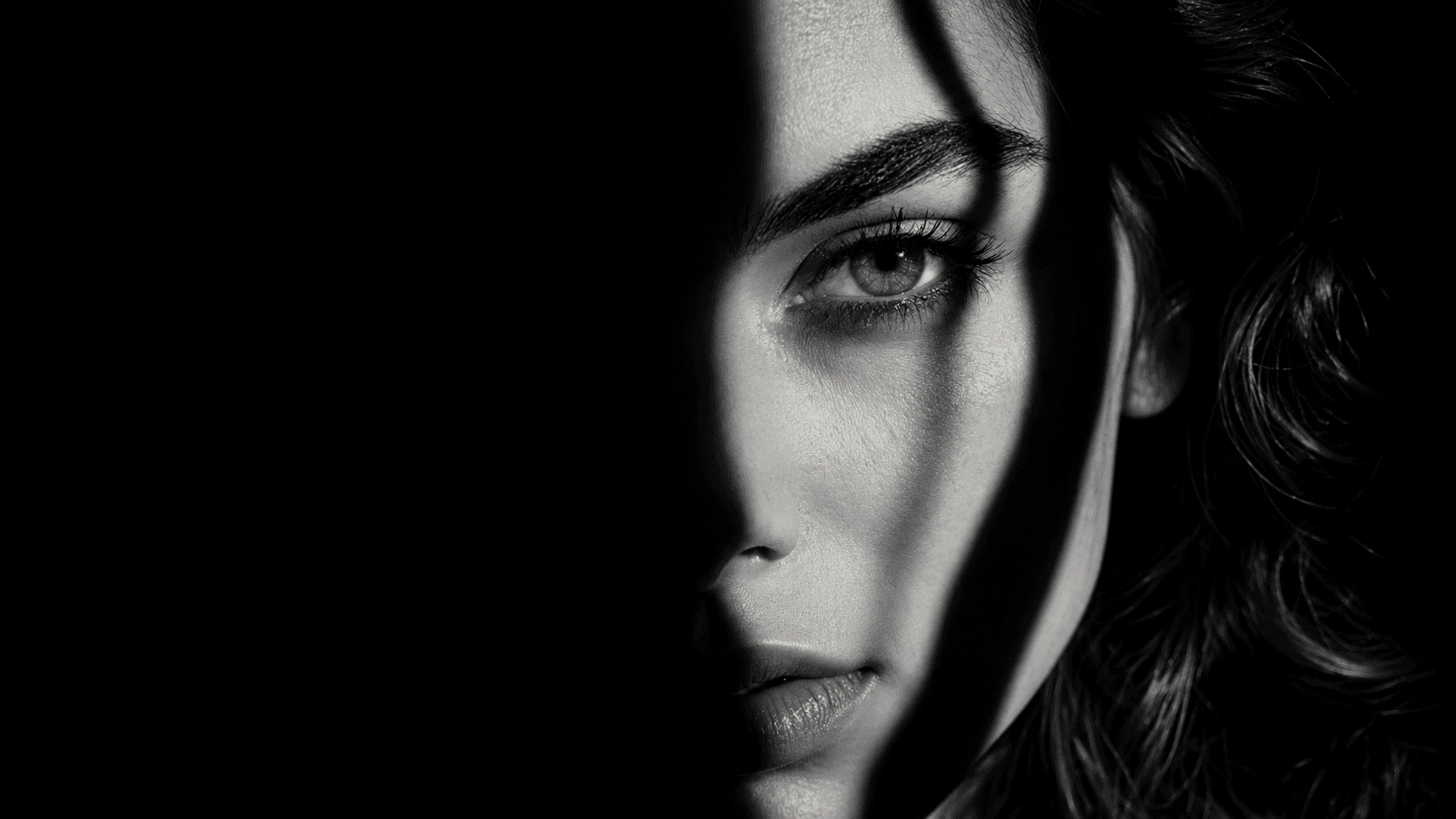 Woman's face half in shadow with a single tear, capturing the isolation of betrayal trauma