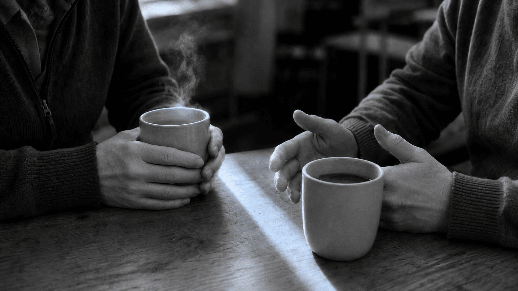 Two people talking over coffee at a wooden table after one of the divorce support groups near me